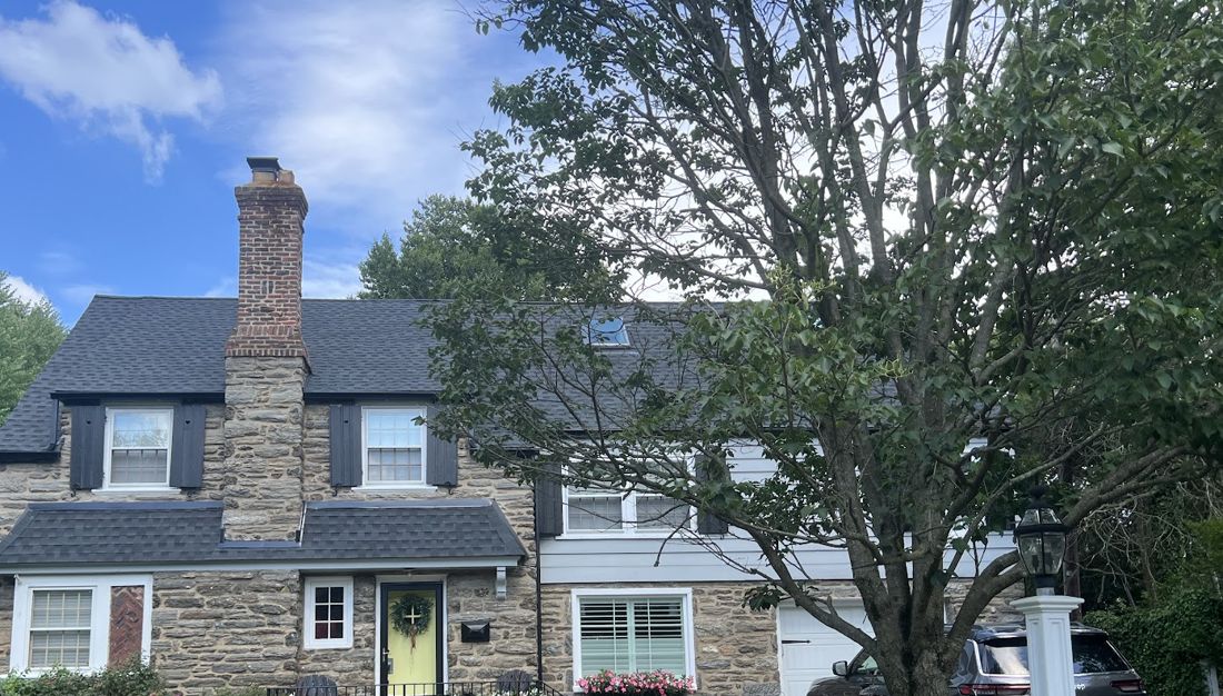 Stone colonial home with new dark shingle roof